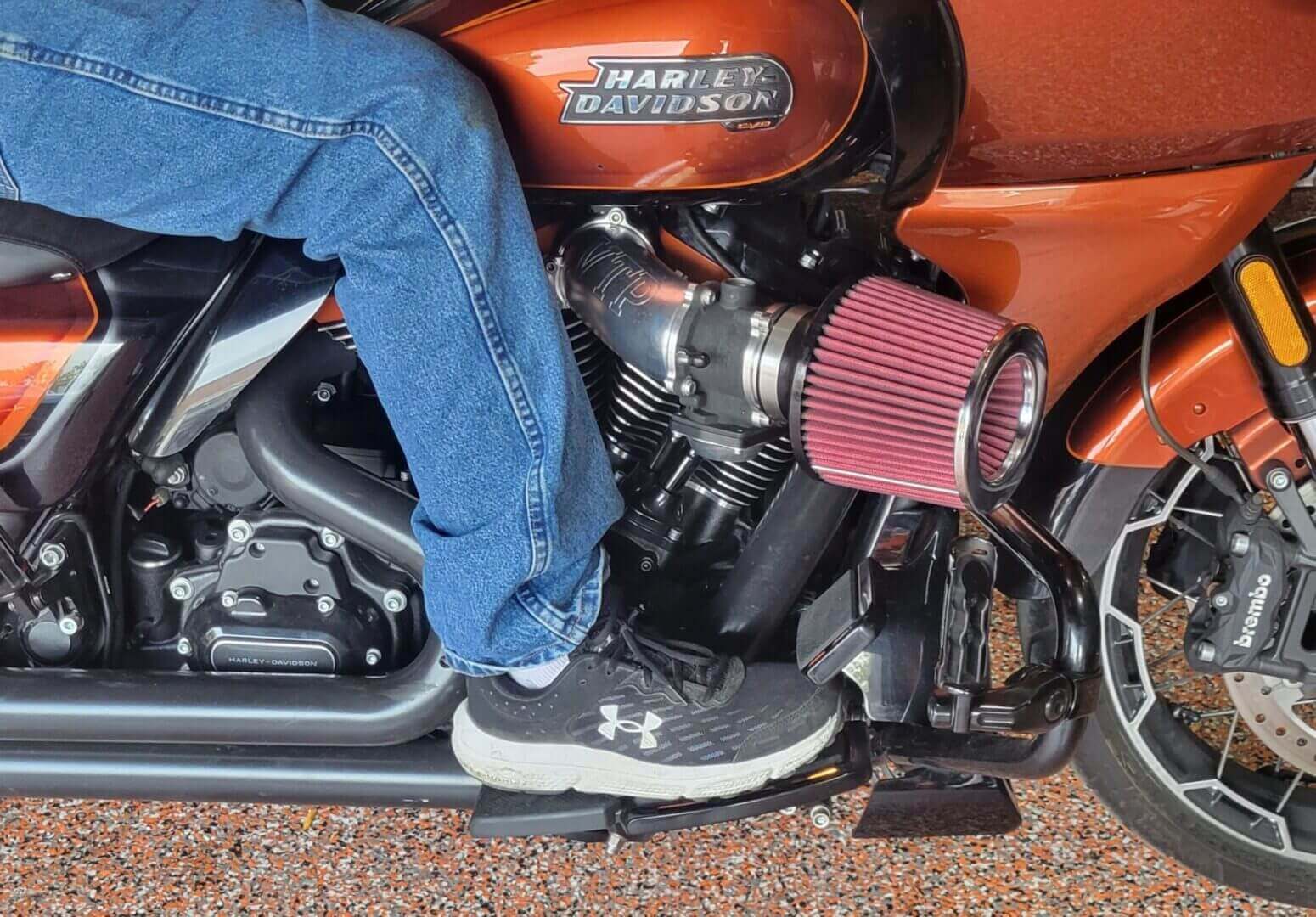 Person sitting on Harley-Davidson motorcycle engine.